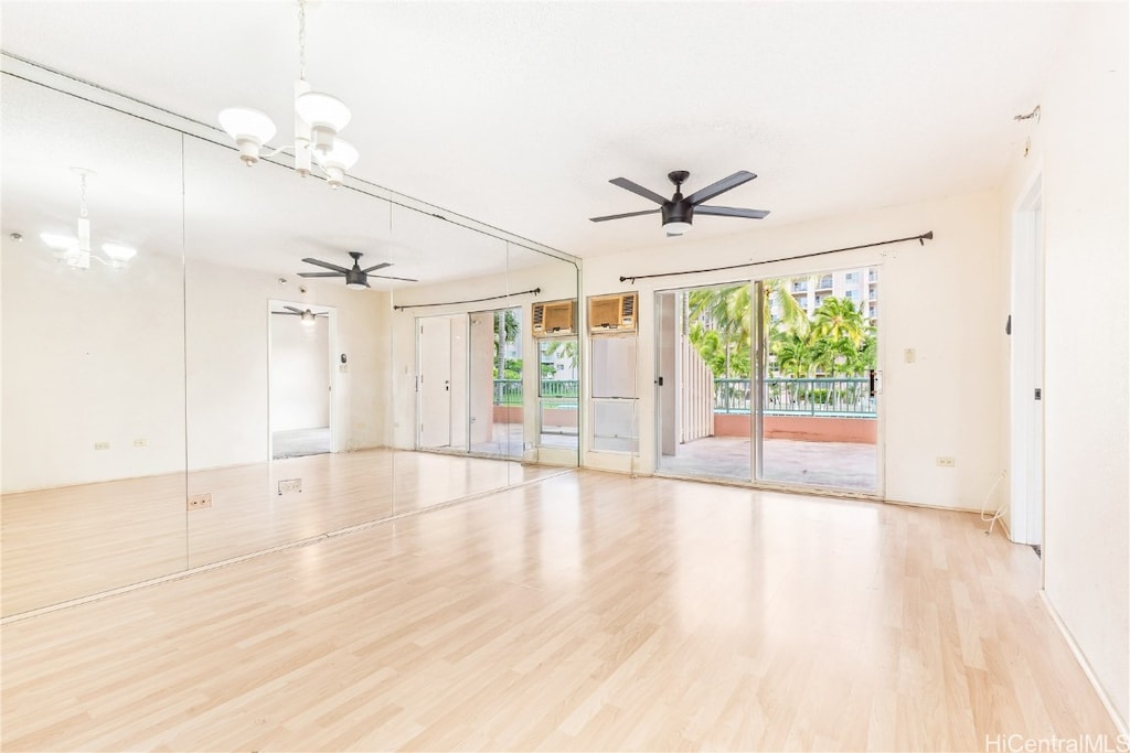 interior space with ceiling fan with notable chandelier and light hardwood / wood-style floors