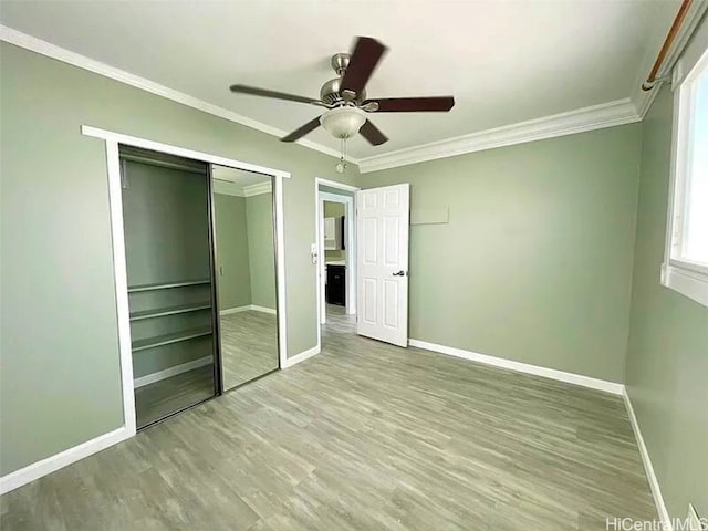 unfurnished bedroom featuring light wood-type flooring, a closet, crown molding, and ceiling fan