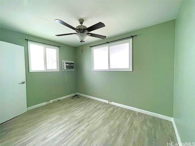 empty room featuring a wall mounted air conditioner, ceiling fan, and light hardwood / wood-style flooring