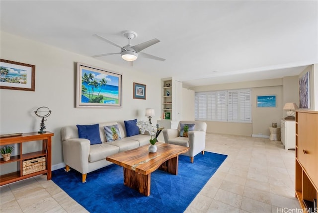 living area featuring built in features, baseboards, and a ceiling fan