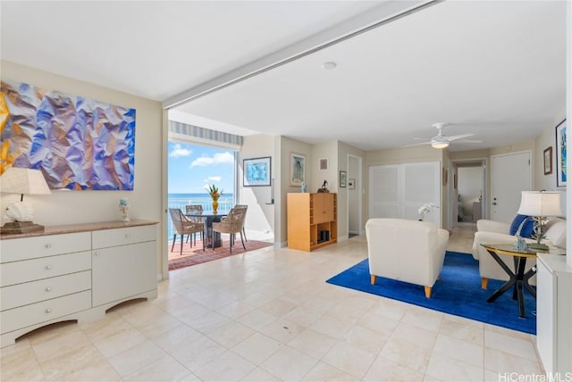 living room featuring ceiling fan and a water view