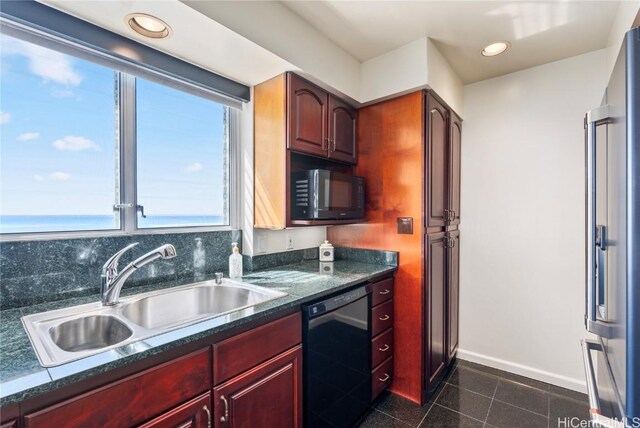 kitchen with tasteful backsplash, dark tile patterned floors, sink, black appliances, and a water view