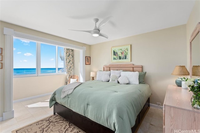 bedroom with a view of the beach, a water view, ceiling fan, and light tile patterned flooring