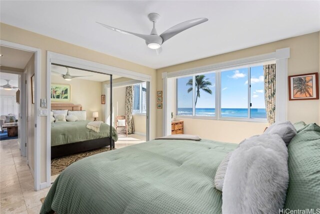 bedroom with ceiling fan, a view of the beach, a water view, a closet, and light tile patterned flooring