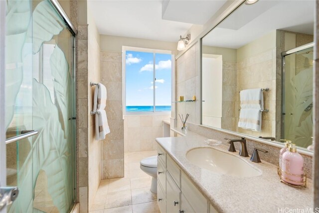 bathroom with walk in shower, tile patterned flooring, toilet, vanity, and tile walls