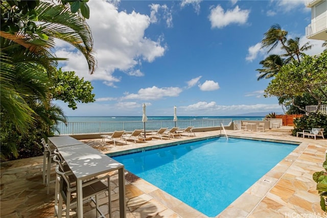 view of swimming pool featuring a water view and a patio