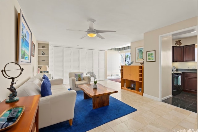 living area with baseboards and ceiling fan