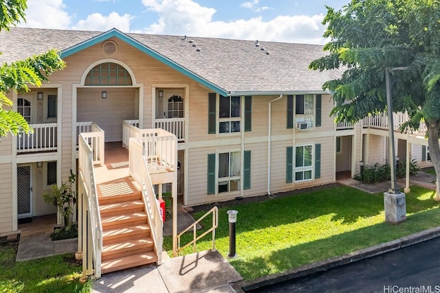 exterior space with roof with shingles, a yard, and stairway