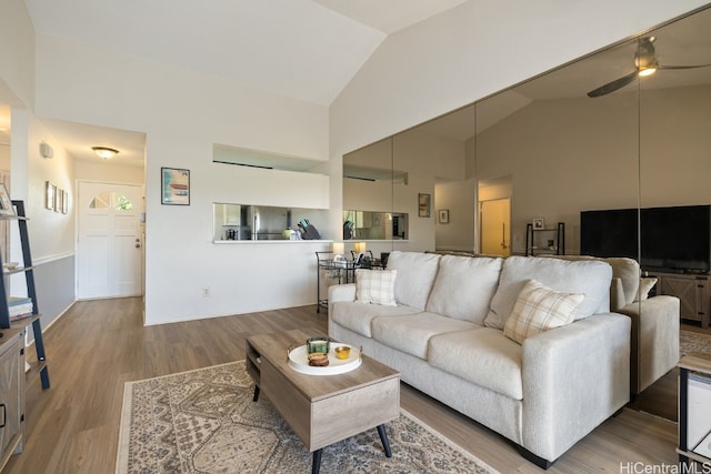 living room with hardwood / wood-style flooring, ceiling fan, and high vaulted ceiling