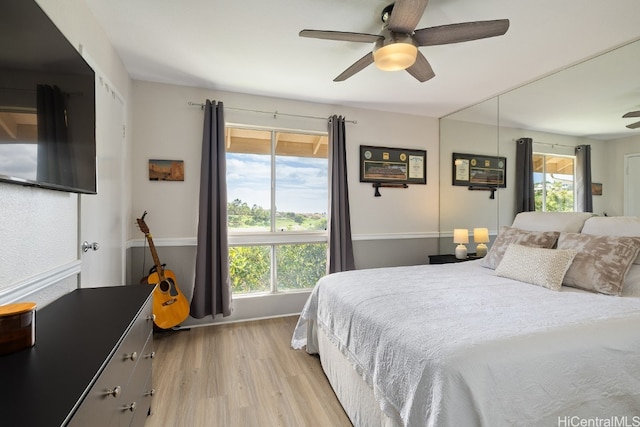 bedroom featuring a ceiling fan, light wood-style flooring, and baseboards