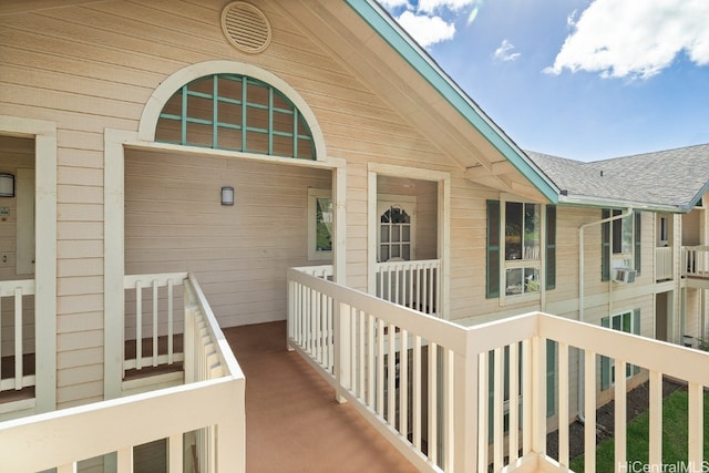 entrance to property featuring a shingled roof and cooling unit