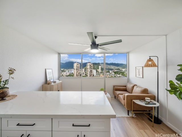 kitchen featuring light stone countertops, ceiling fan, white cabinets, and light hardwood / wood-style floors