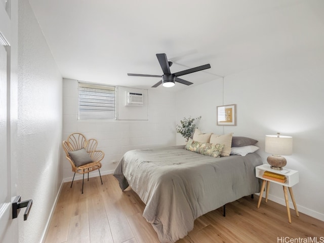 bedroom featuring a wall mounted air conditioner, light hardwood / wood-style flooring, and ceiling fan