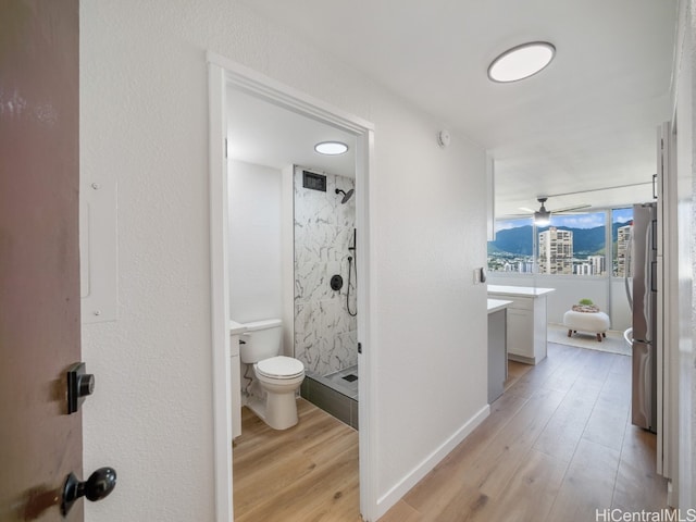 bathroom featuring vanity, ceiling fan, wood-type flooring, and tiled shower