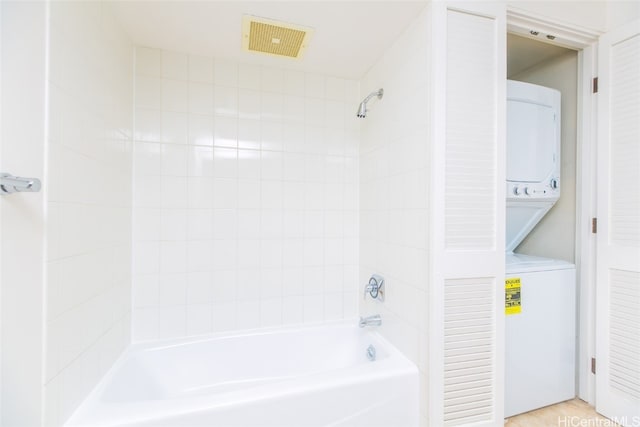 bathroom with wood-type flooring, tiled shower / bath, and stacked washer and clothes dryer