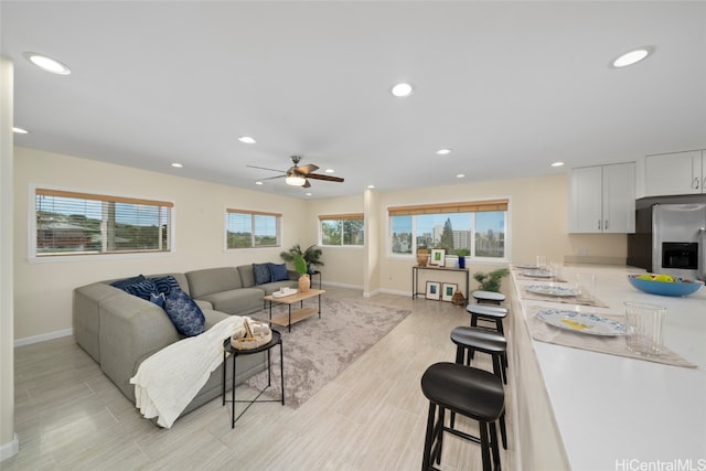 living room featuring a wealth of natural light, ceiling fan, and light wood-type flooring