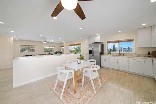 dining space with ceiling fan, light hardwood / wood-style flooring, a wealth of natural light, and sink