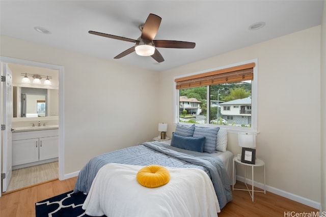 bedroom featuring connected bathroom, ceiling fan, sink, and light wood-type flooring