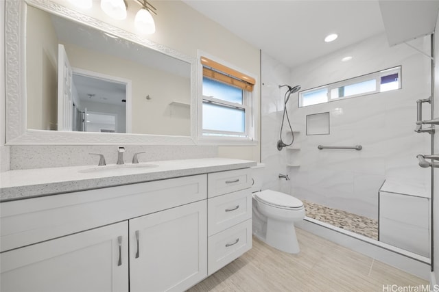 bathroom featuring a tile shower, vanity, and toilet