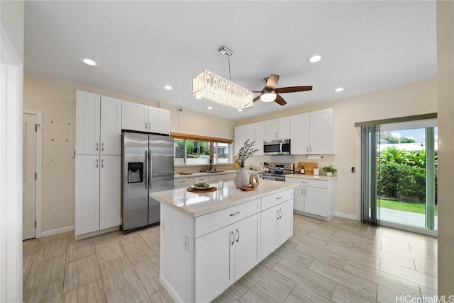 kitchen with white cabinetry, a center island, stainless steel appliances, and decorative light fixtures