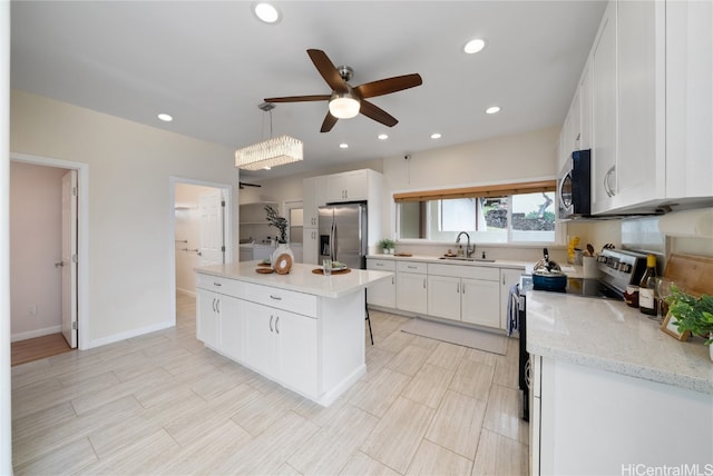 kitchen featuring stainless steel appliances, sink, white cabinets, a center island, and hanging light fixtures