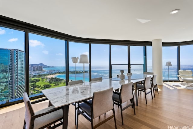 dining space featuring hardwood / wood-style floors, a water view, and expansive windows