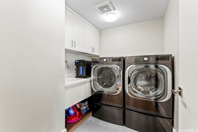 washroom with washing machine and clothes dryer, hardwood / wood-style floors, and cabinets