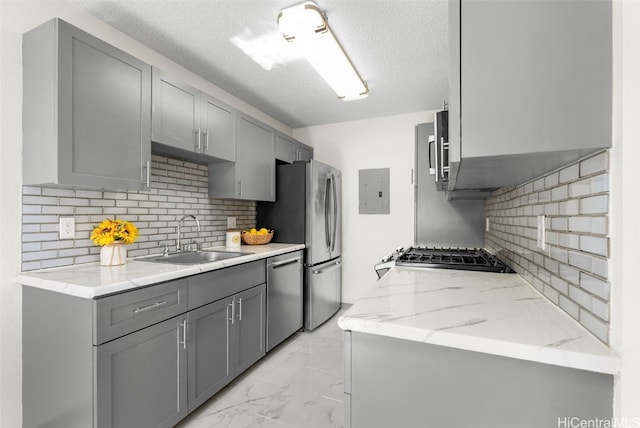 kitchen with backsplash, gray cabinetry, a textured ceiling, stainless steel appliances, and sink