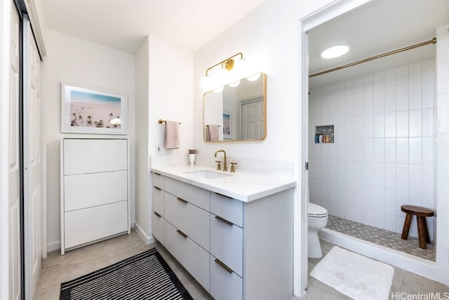 bathroom featuring tiled shower, tile patterned flooring, vanity, and toilet