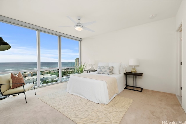 carpeted bedroom featuring ceiling fan, a water view, and a wall of windows