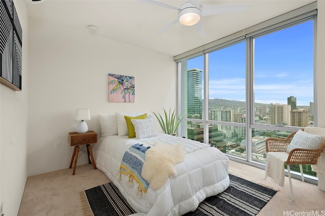 bedroom with multiple windows, light carpet, ceiling fan, and expansive windows