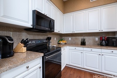 kitchen with black electric range, white cabinets, light stone counters, and dark wood-type flooring