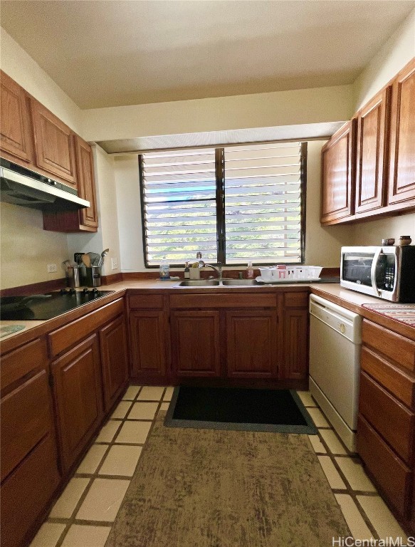 kitchen featuring dishwasher, light tile patterned floors, black stovetop, and sink