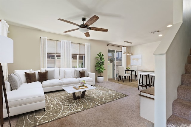 carpeted living room featuring ceiling fan with notable chandelier