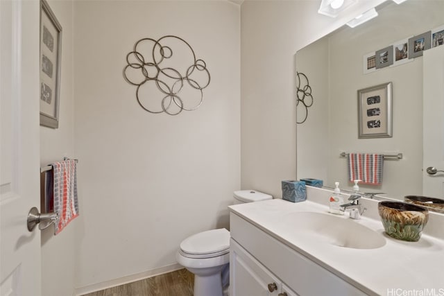 bathroom featuring toilet, vanity, and hardwood / wood-style flooring