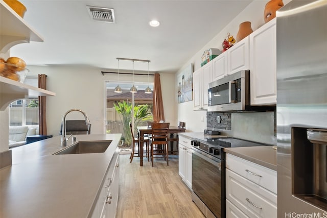 kitchen featuring sink, hanging light fixtures, light hardwood / wood-style floors, white cabinetry, and stainless steel appliances