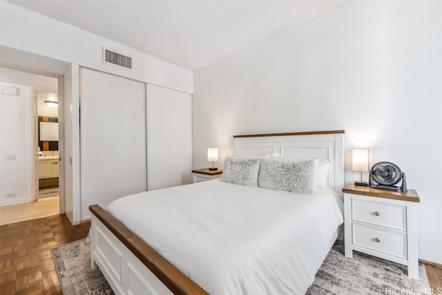 bedroom featuring ensuite bath, a closet, and dark parquet floors