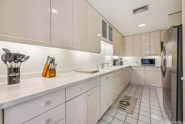 kitchen with white cabinets, sink, light tile patterned floors, and appliances with stainless steel finishes