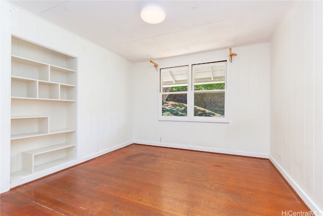 empty room with hardwood / wood-style floors and built in features