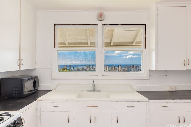 kitchen featuring white cabinetry, plenty of natural light, white gas range oven, and decorative backsplash