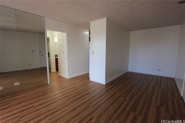 spare room featuring a textured ceiling and dark wood-type flooring