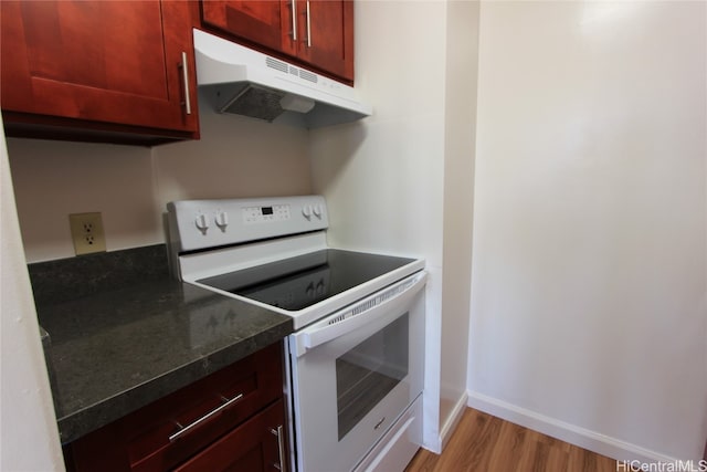 kitchen featuring white range with electric stovetop, dark stone counters, and light hardwood / wood-style flooring