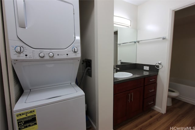 washroom with stacked washer / dryer, sink, and dark hardwood / wood-style floors