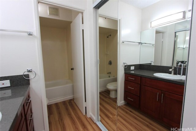 full bathroom with hardwood / wood-style floors, vanity, toilet, and shower / bathtub combination