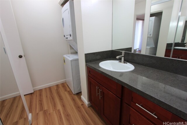 bathroom with vanity, wood-type flooring, and stacked washer and clothes dryer