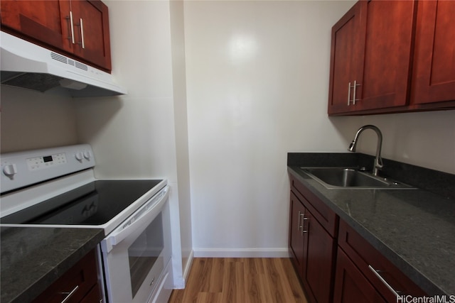 kitchen with light hardwood / wood-style flooring, white range with electric cooktop, dark stone countertops, and sink