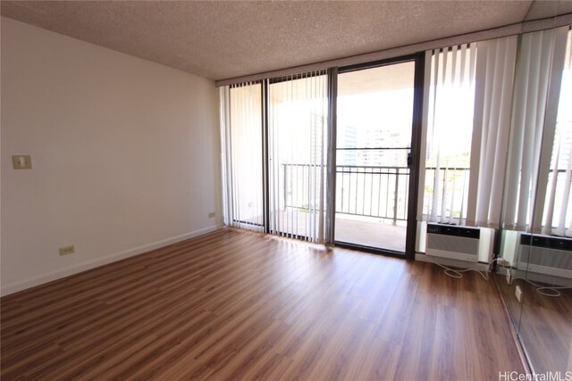 empty room featuring dark hardwood / wood-style flooring, a textured ceiling, and a wall of windows