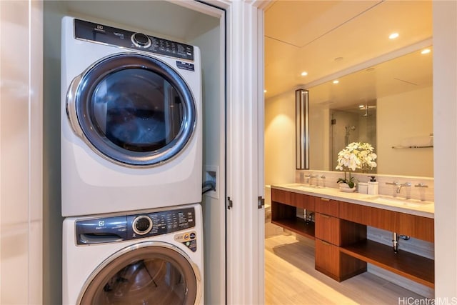 washroom with stacked washer / drying machine, light hardwood / wood-style floors, and sink