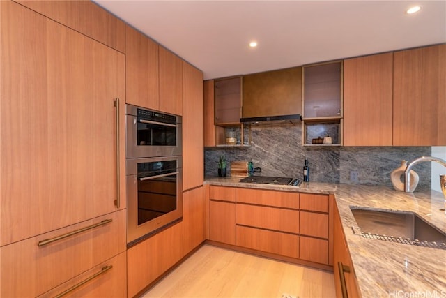 kitchen with black gas cooktop, sink, backsplash, stainless steel double oven, and light hardwood / wood-style flooring