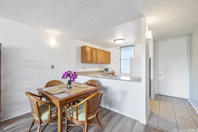 kitchen with kitchen peninsula, white fridge, a textured ceiling, and light wood-type flooring